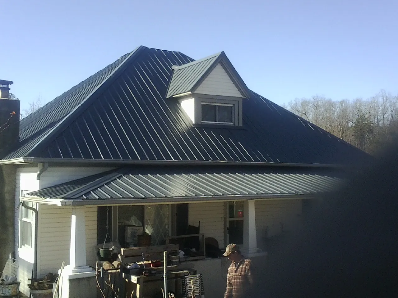 Dark blue standing seam metal roof with a dormer above a front porch in Chichester