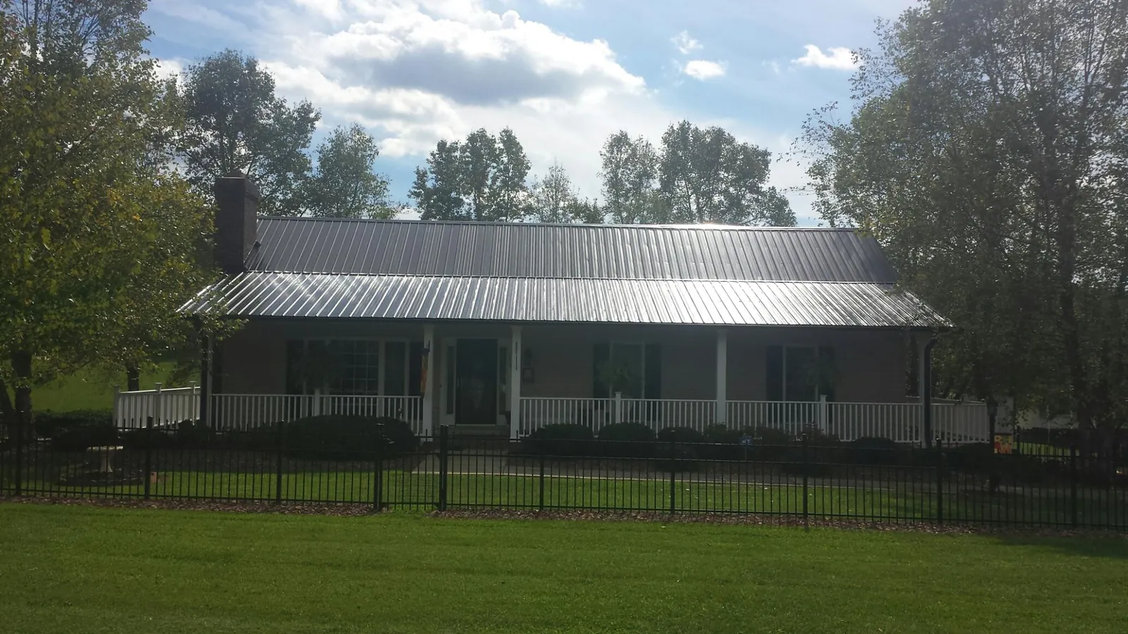 Gray metal roof on a brick ranch with a full width front porch — Gutter Guard Installation work by our crew in Chichester