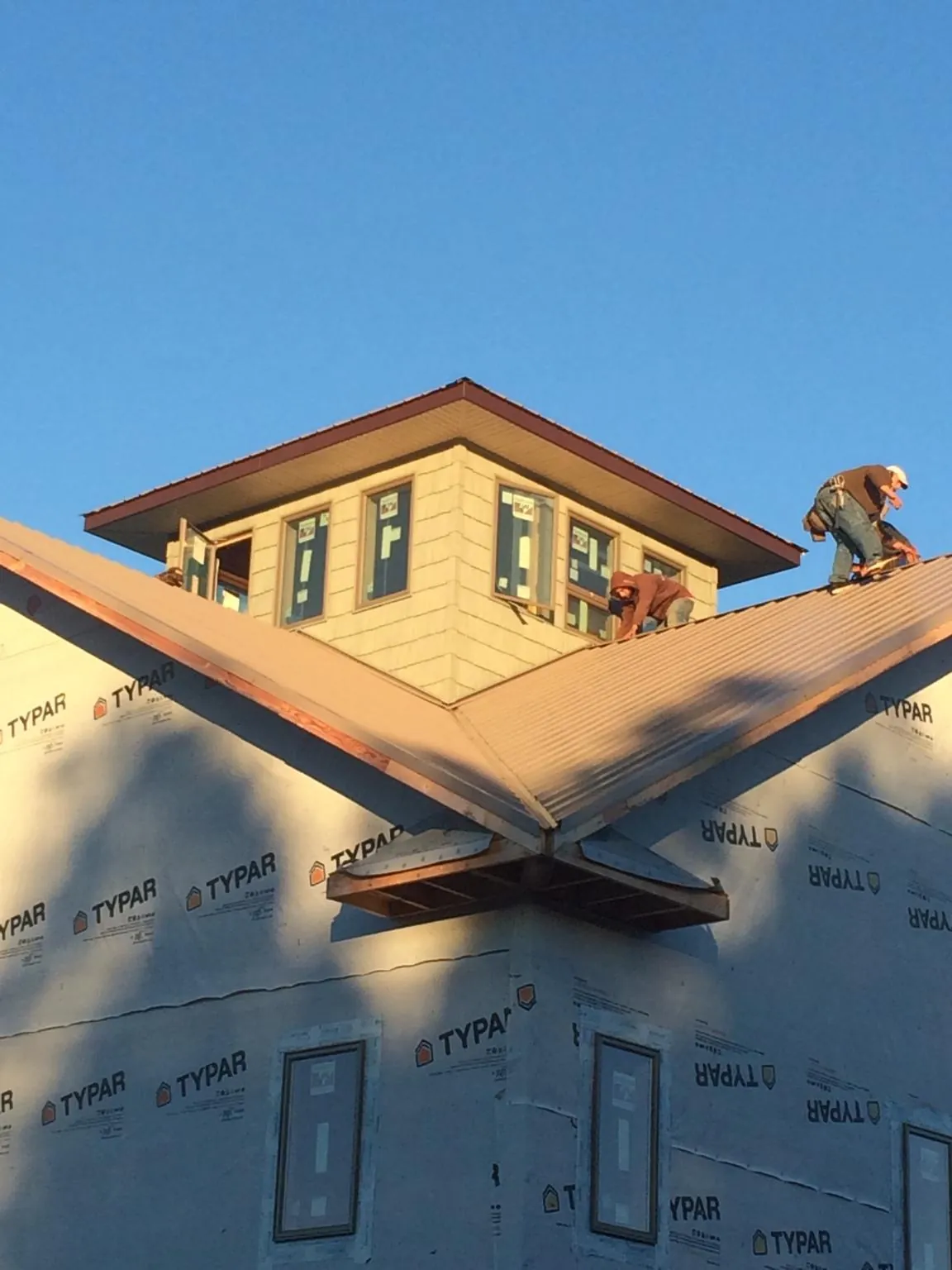Roofers working around a rooftop cupola on a new metal roof at sunset — Roof Waterproofing in Chichester by Roofing Brothers